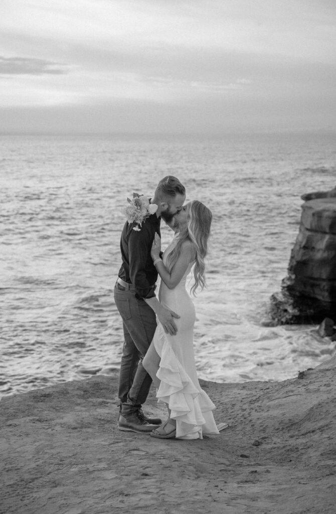 Couple kissing on their elopement day at Sunset Cliffs, San Diego after saying their vows.