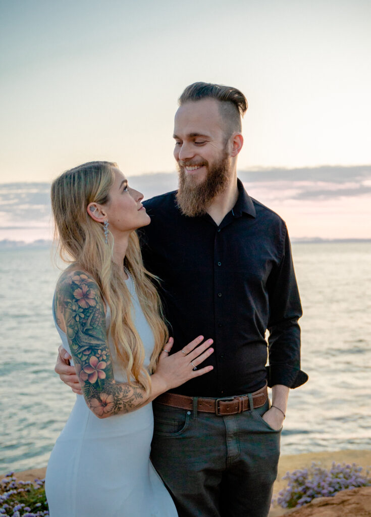 couple looking at each other with the ocean behind them at Sunset Cliffs San Diego