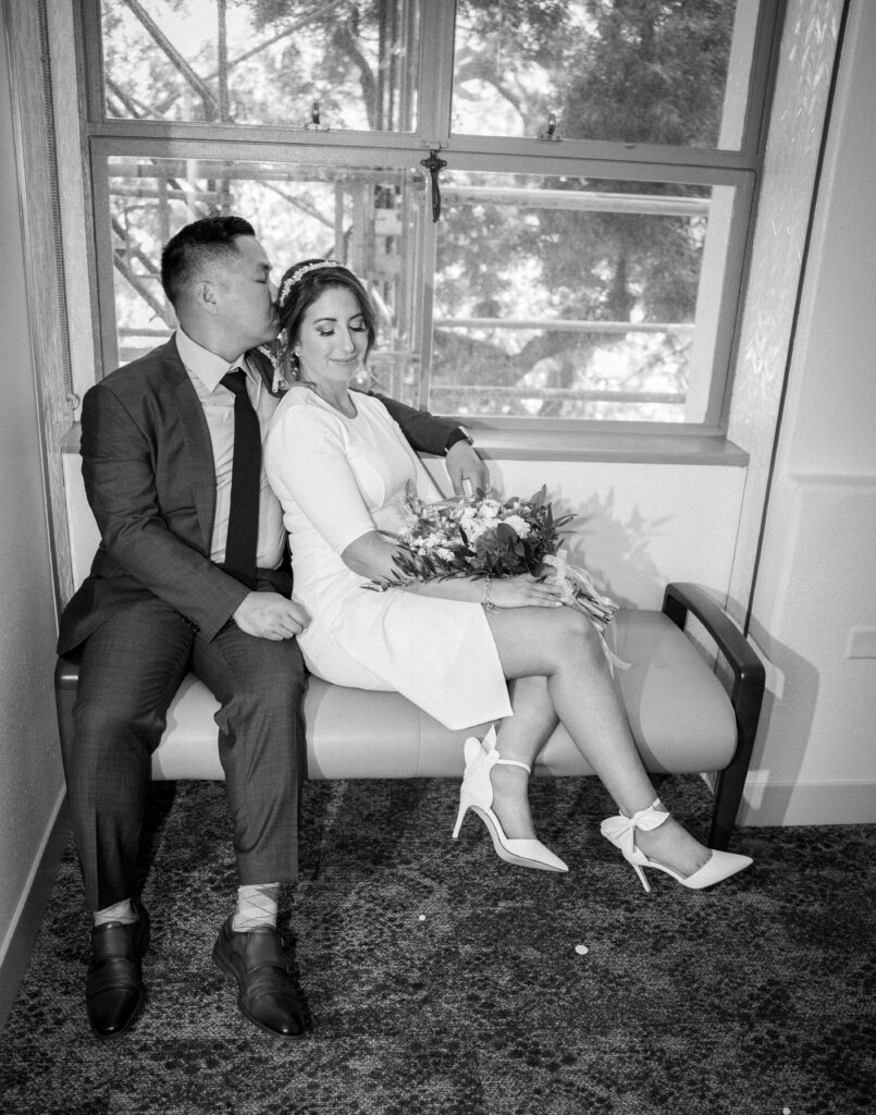 Groom kissing bride at San Diego courthouse before their wedding ceremony.