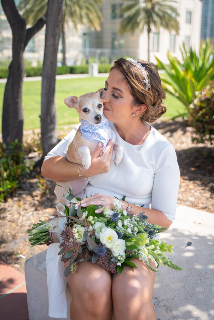 Bride kissing her pup on her wedding day at the San Diego courthouse.