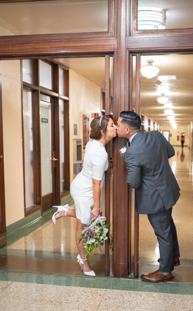 Couple kissing in San Diego courthouse waiting for their marriage certificate.