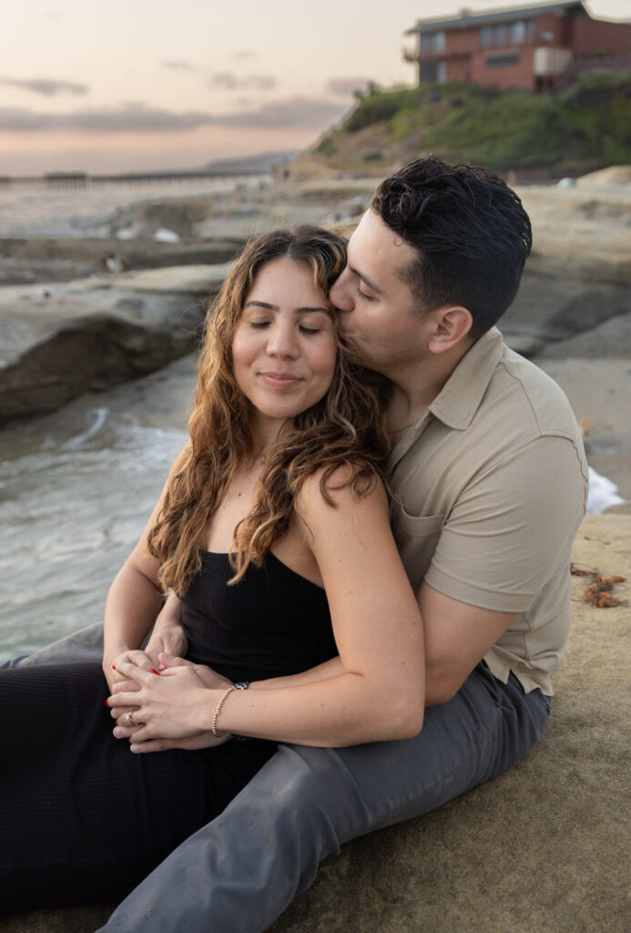 partner giving fiancee kiss on her cheek at sunset cliffs