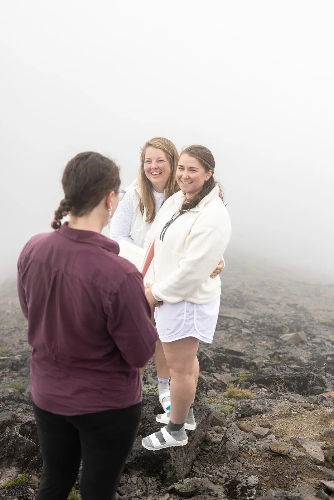 Mt. Rainier elopement ceremony in dense fog on Burroughs Mountain, officiant facing the couple