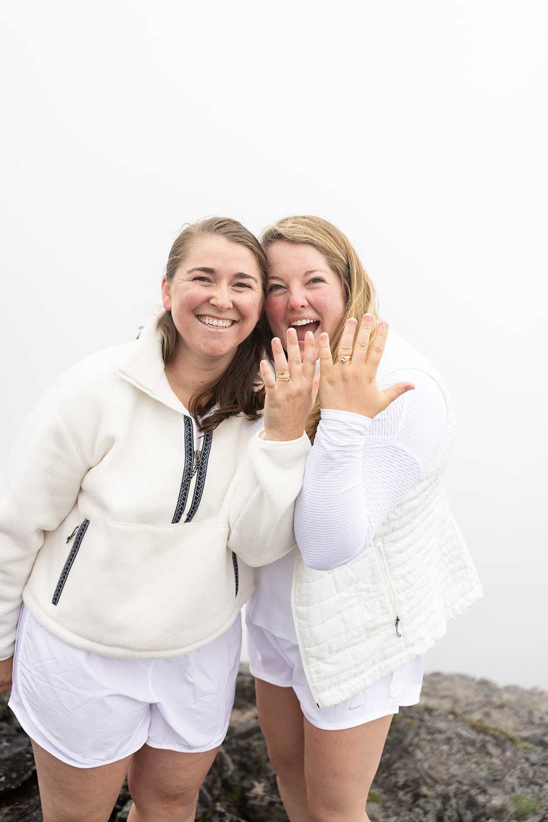 Two brides laughing as they show their wedding rings after eloping at Mt. Rainier