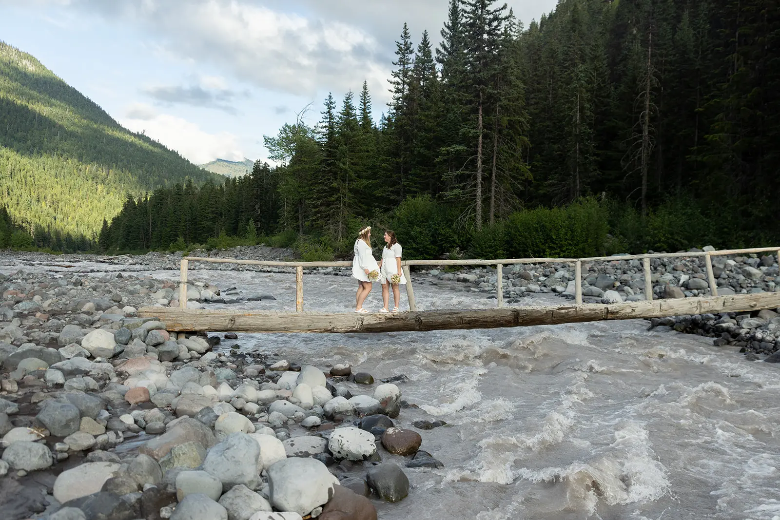Couple walking across the wooden footbridge over the White River on the Wonderland Trail at Mt. Rainier