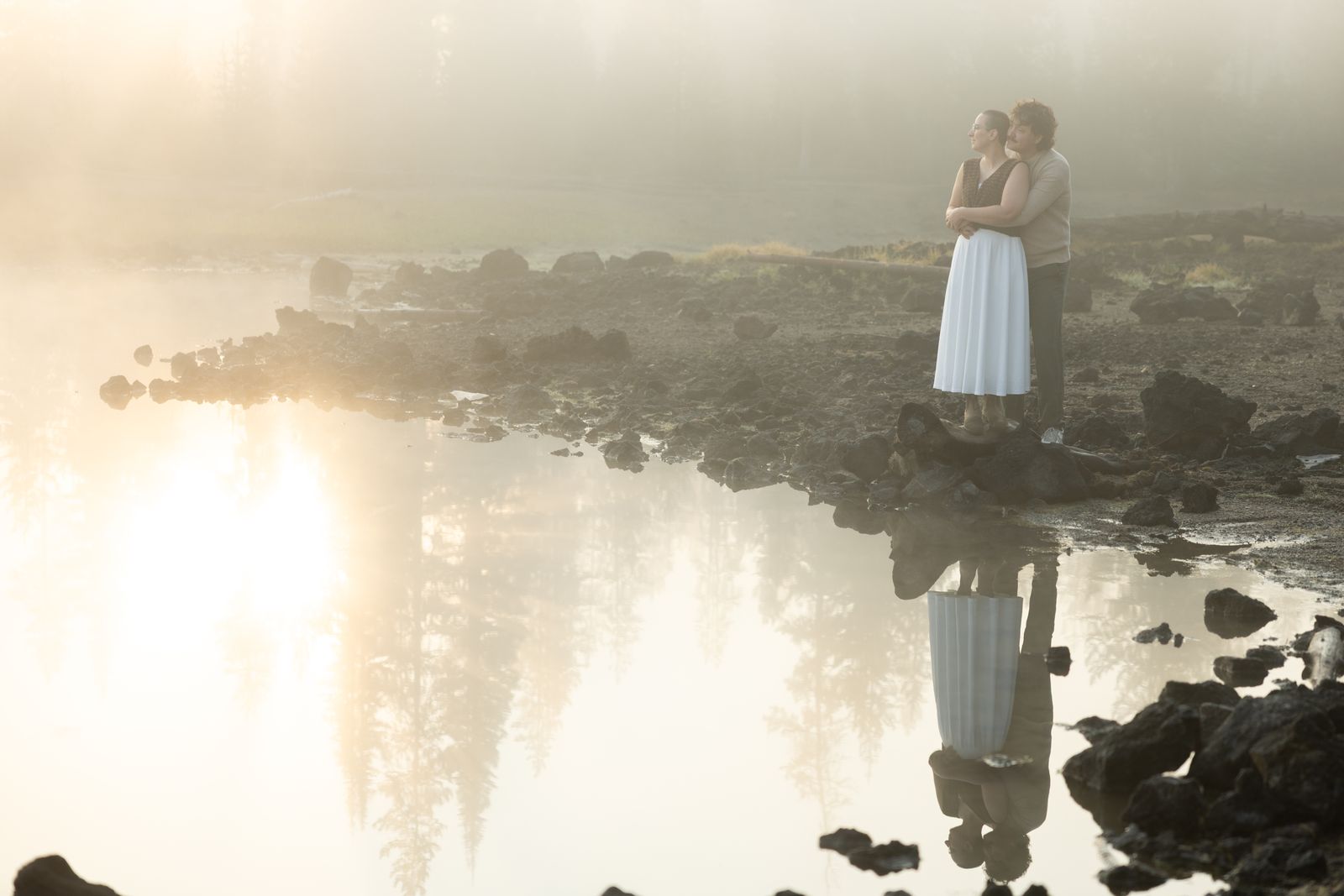 Reflection of an engaged couple in the still water of Sparks Lake at sunrise in Central Oregon