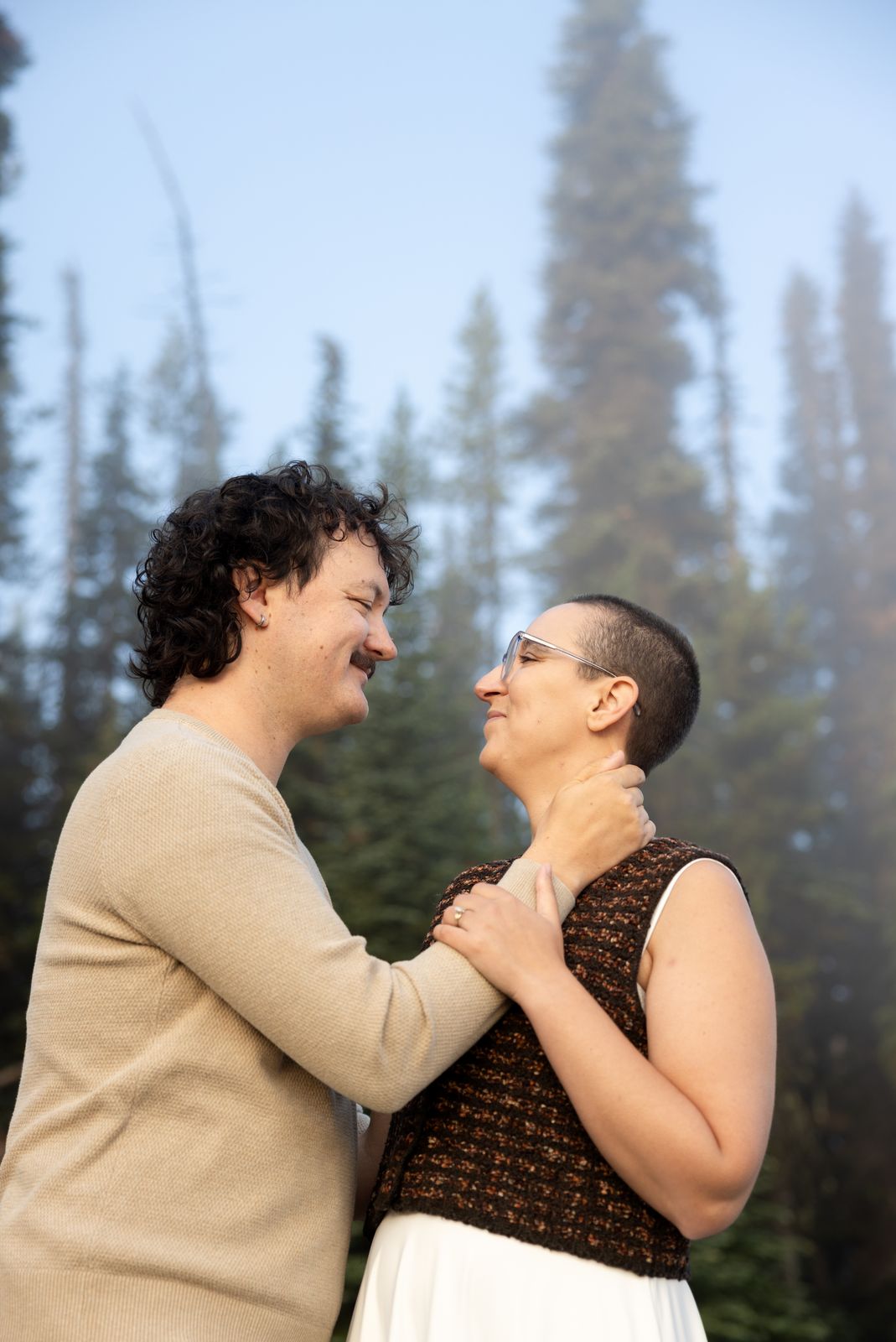 Couple laughing face to face in fog among lodgepole pines at Sparks Lake Oregon